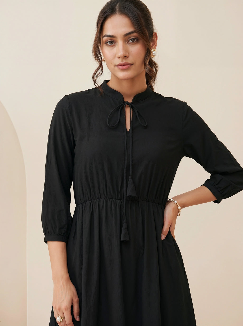 Woman wearing a black dress against a beige background