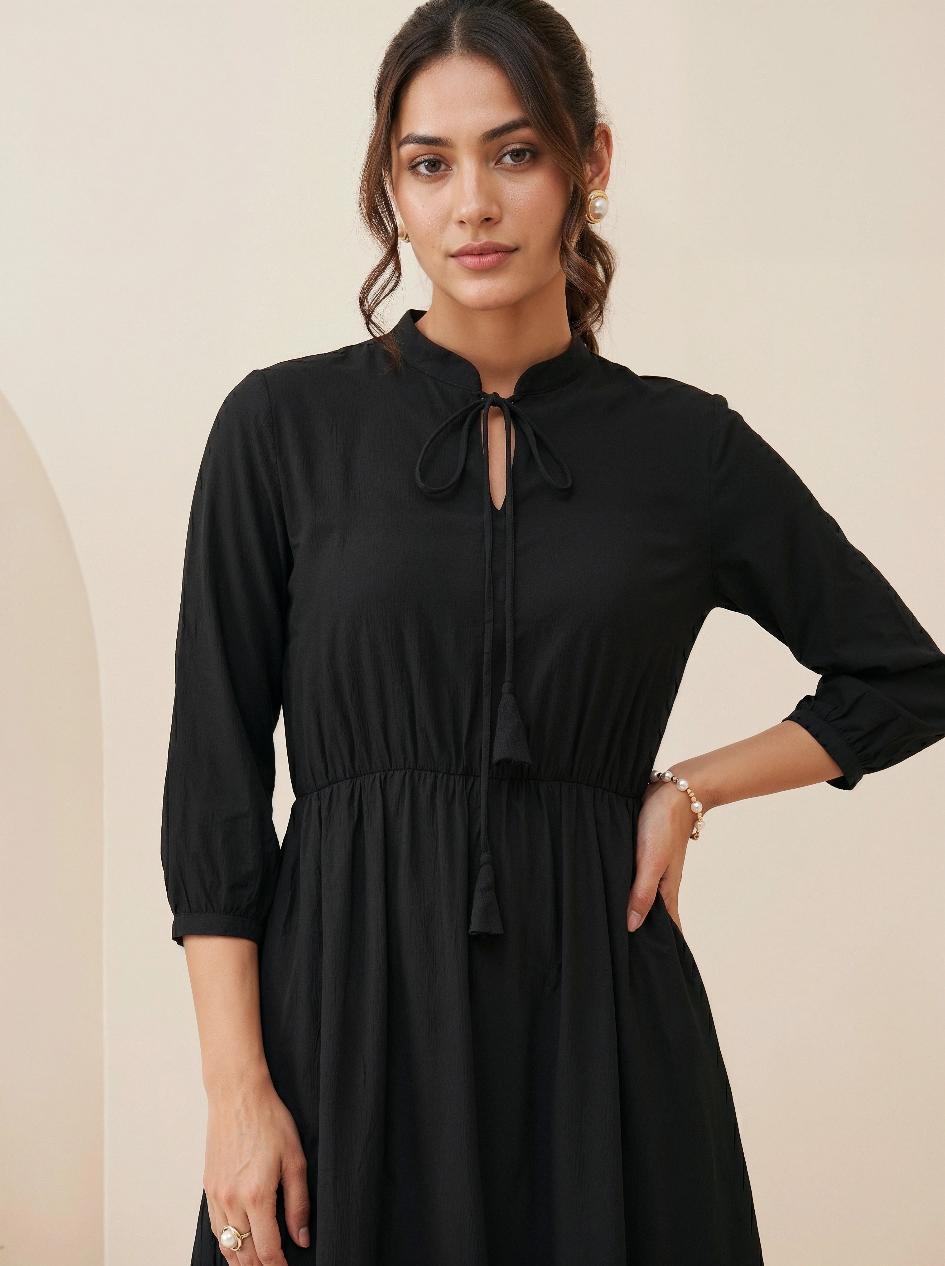 Woman wearing a black dress against a beige background