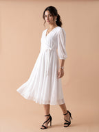 Woman wearing a white dress with puff sleeves on a beige background