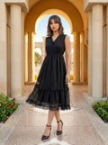 Woman in a black dress standing in an architectural setting with columns and arches.