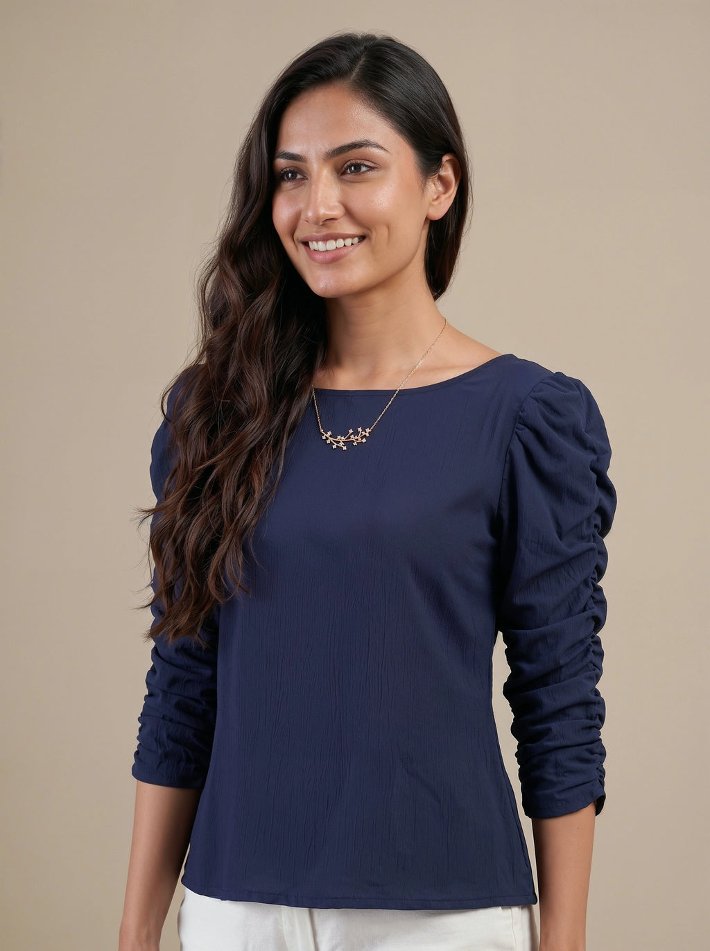 Woman wearing a navy blue long-sleeve top against a beige background