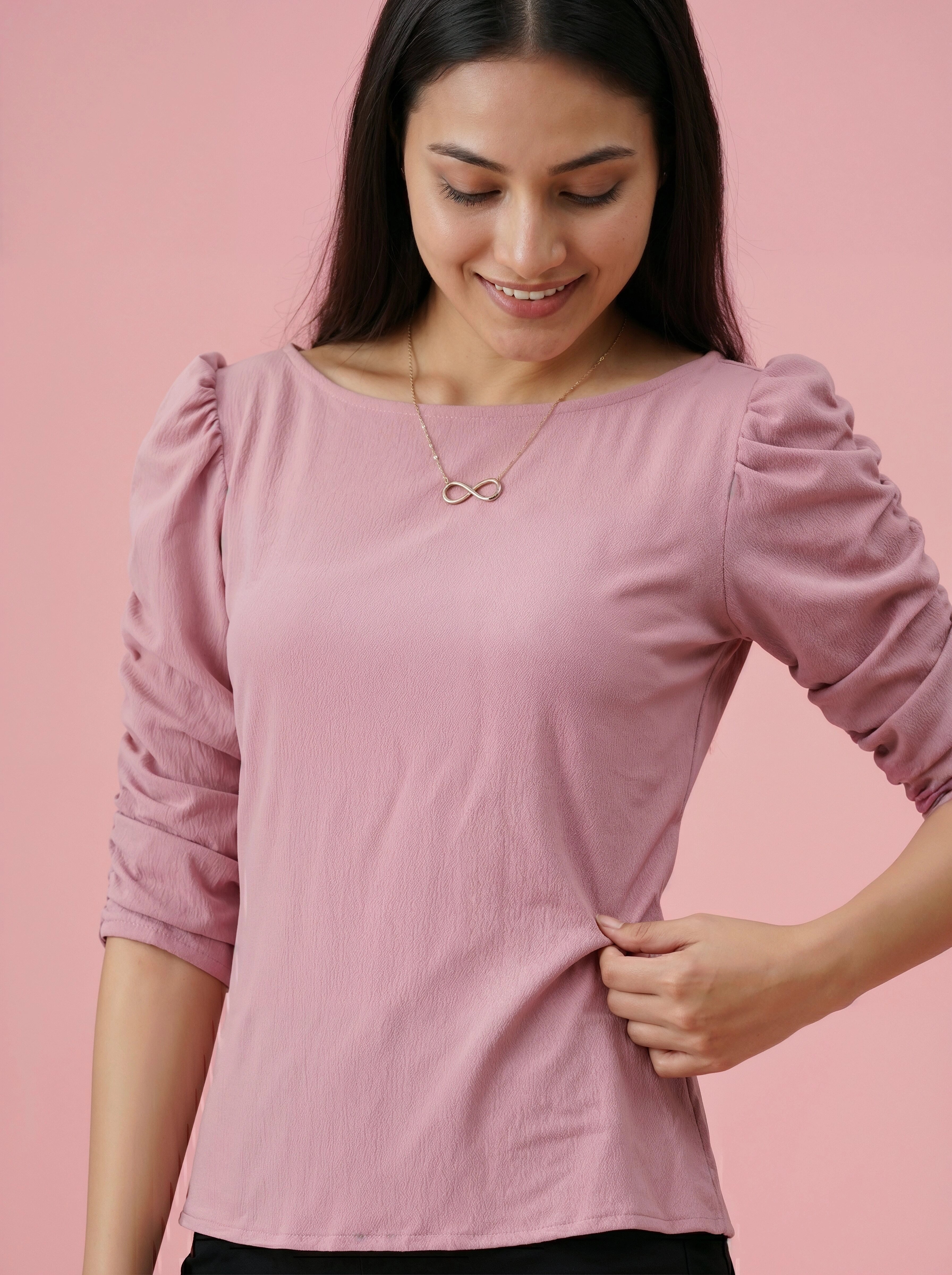 Woman wearing a pink long-sleeve top against a pink background