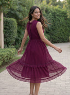 Woman in a purple dress walking outdoors on a paved path with greenery.