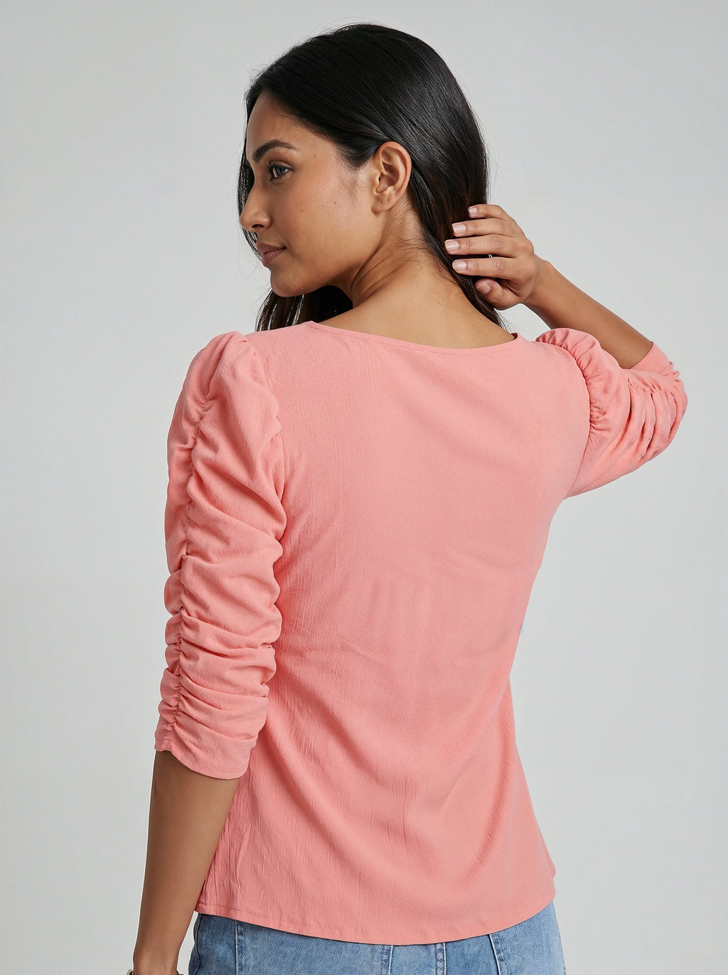 Woman wearing a pink long-sleeve top against a plain background