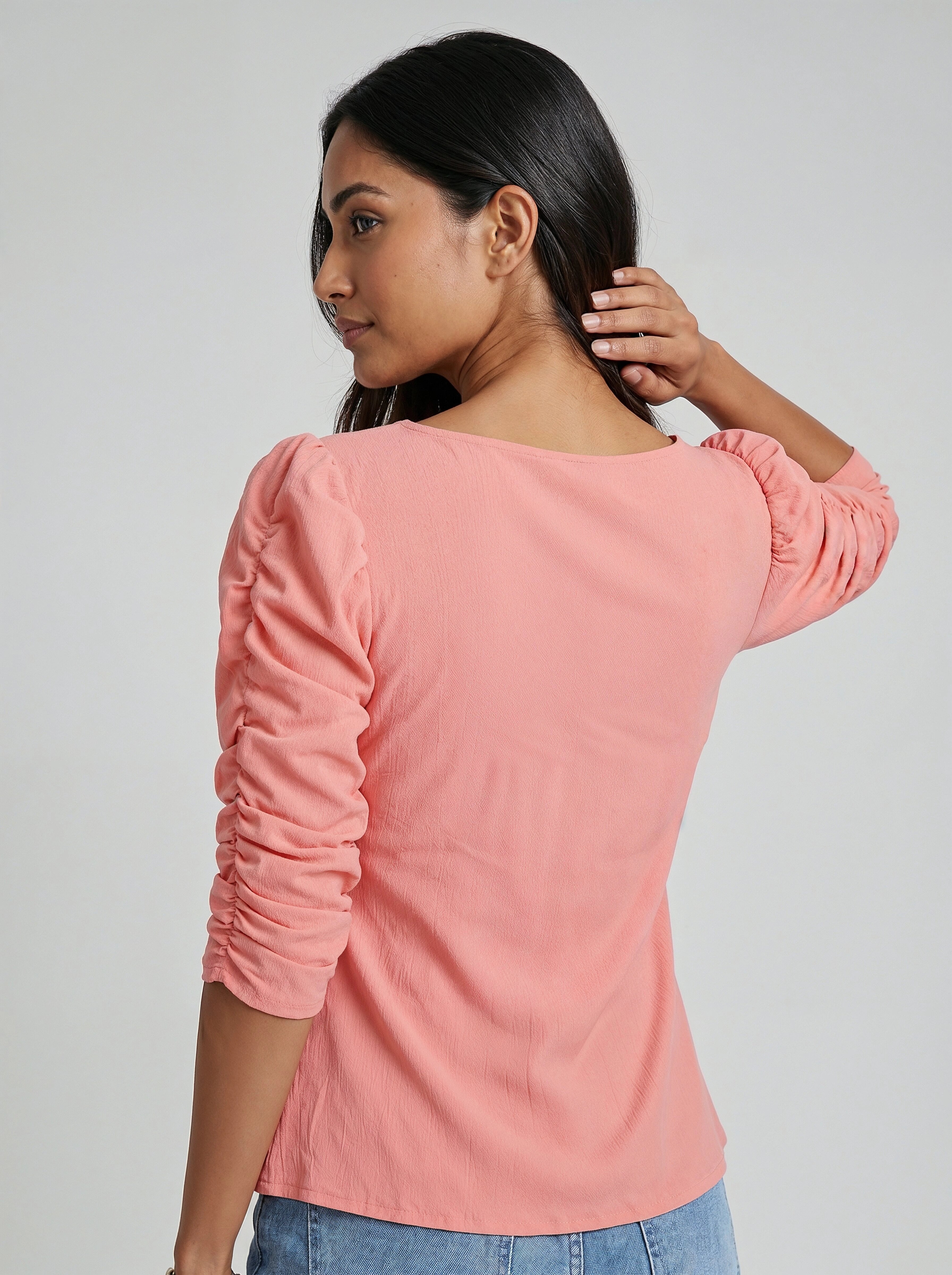 Woman wearing a pink long-sleeve top against a plain background