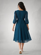 Woman wearing a blue dress with a subtle pattern on a plain background