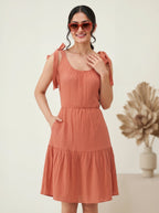 Woman wearing a terracotta dress with ruffled sleeves against a neutral background