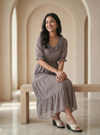 Woman in a long dress sitting on a bench in a sunlit room with arched ceilings.