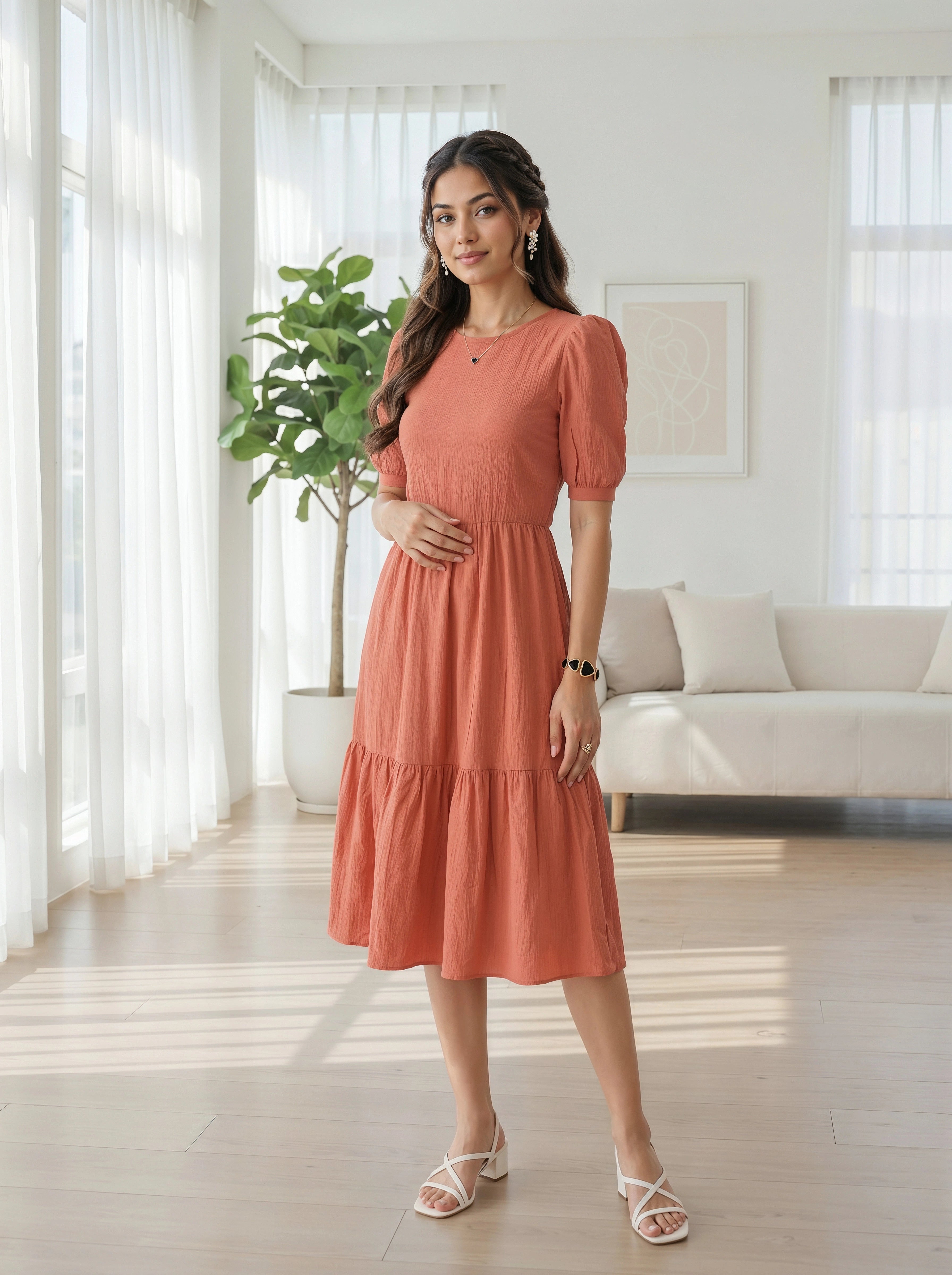 Woman in a coral dress standing in a bright living room.