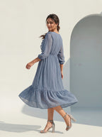 Woman wearing a blue dress standing against a light background