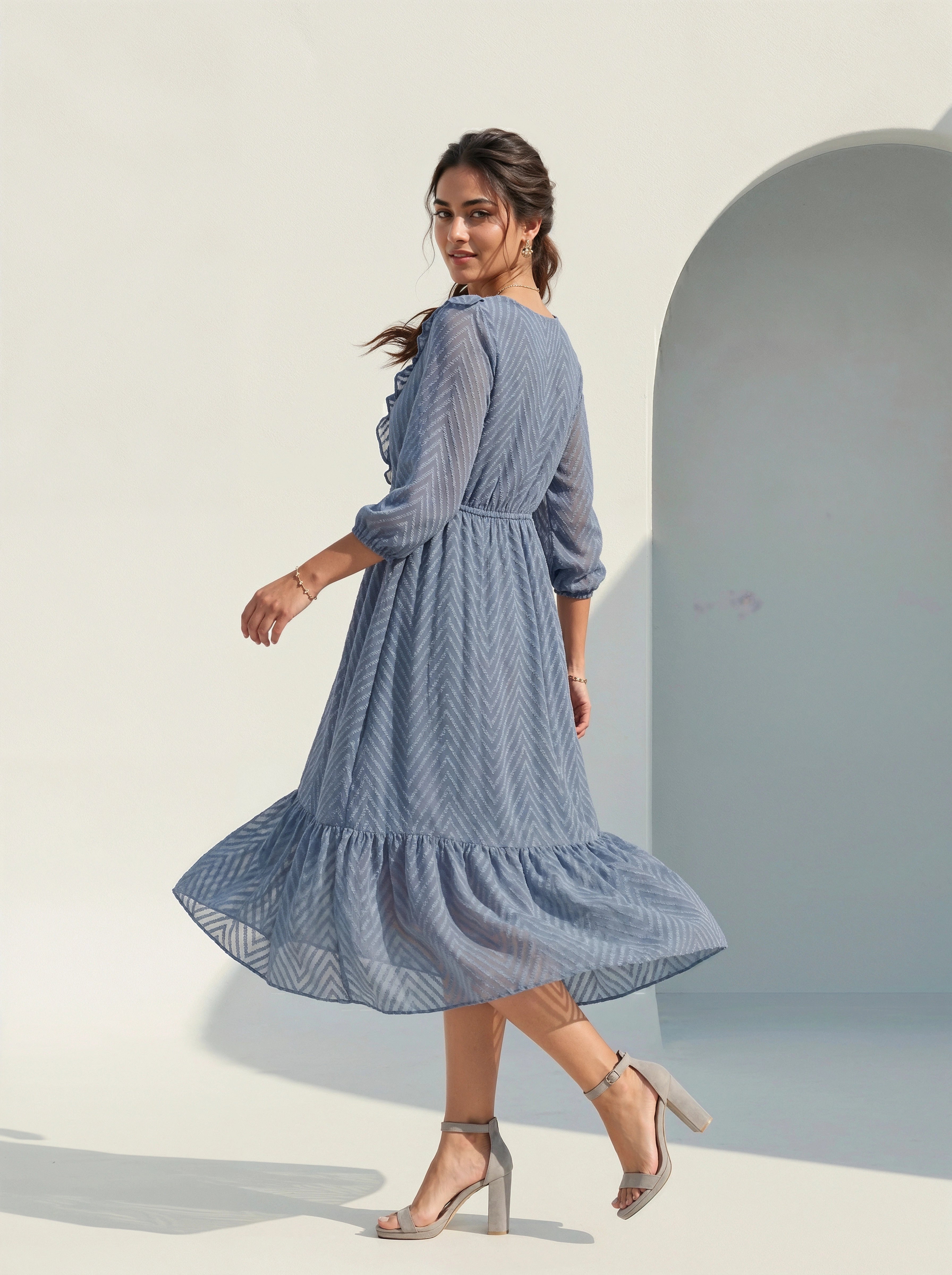 Woman wearing a blue dress standing against a light background
