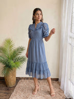 Woman wearing a textured light blue dress paired with nude heels