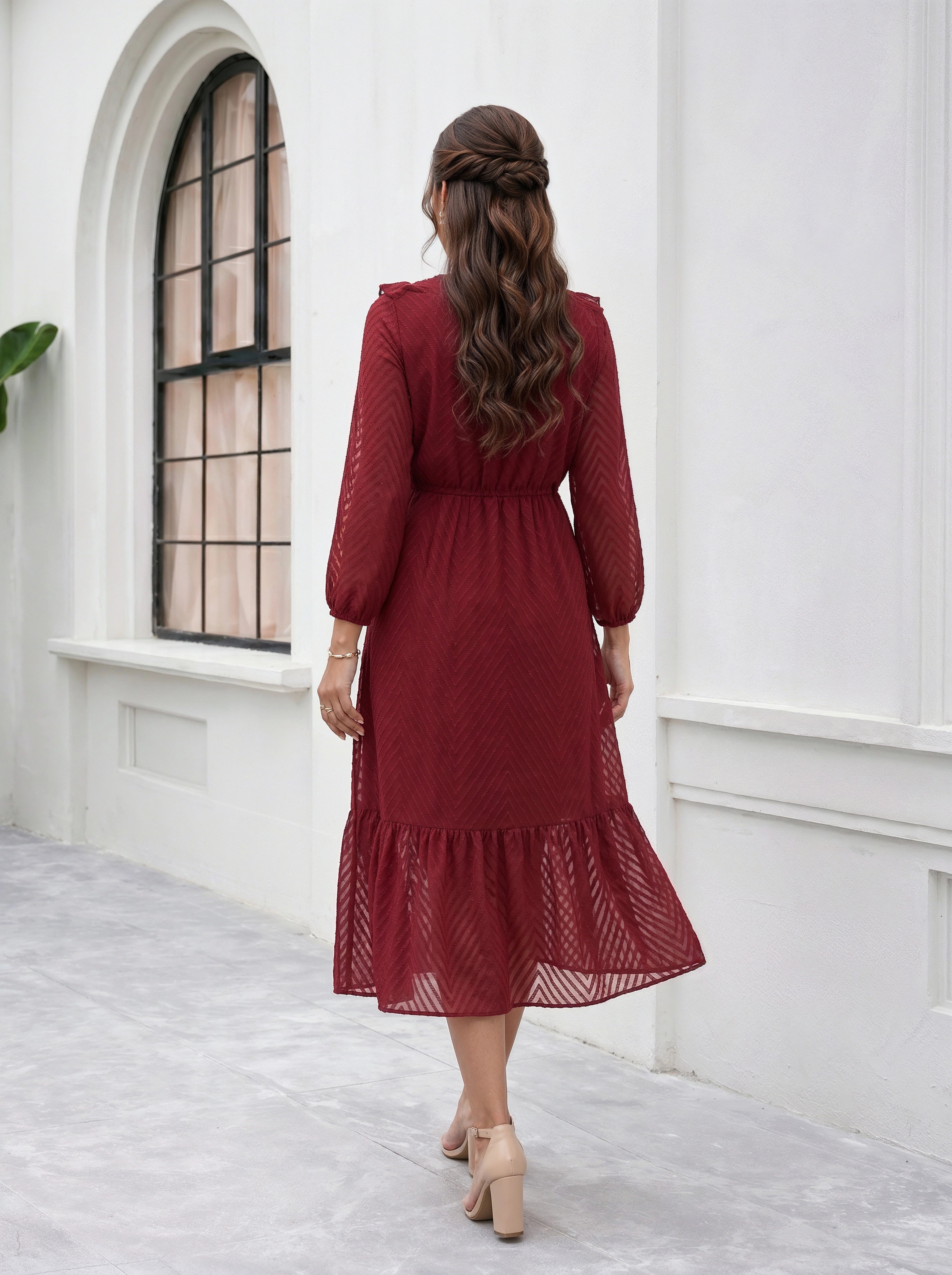 Woman in a red dress standing in a white room with a window.