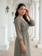 Woman in a green dress standing in a white architectural hallway
