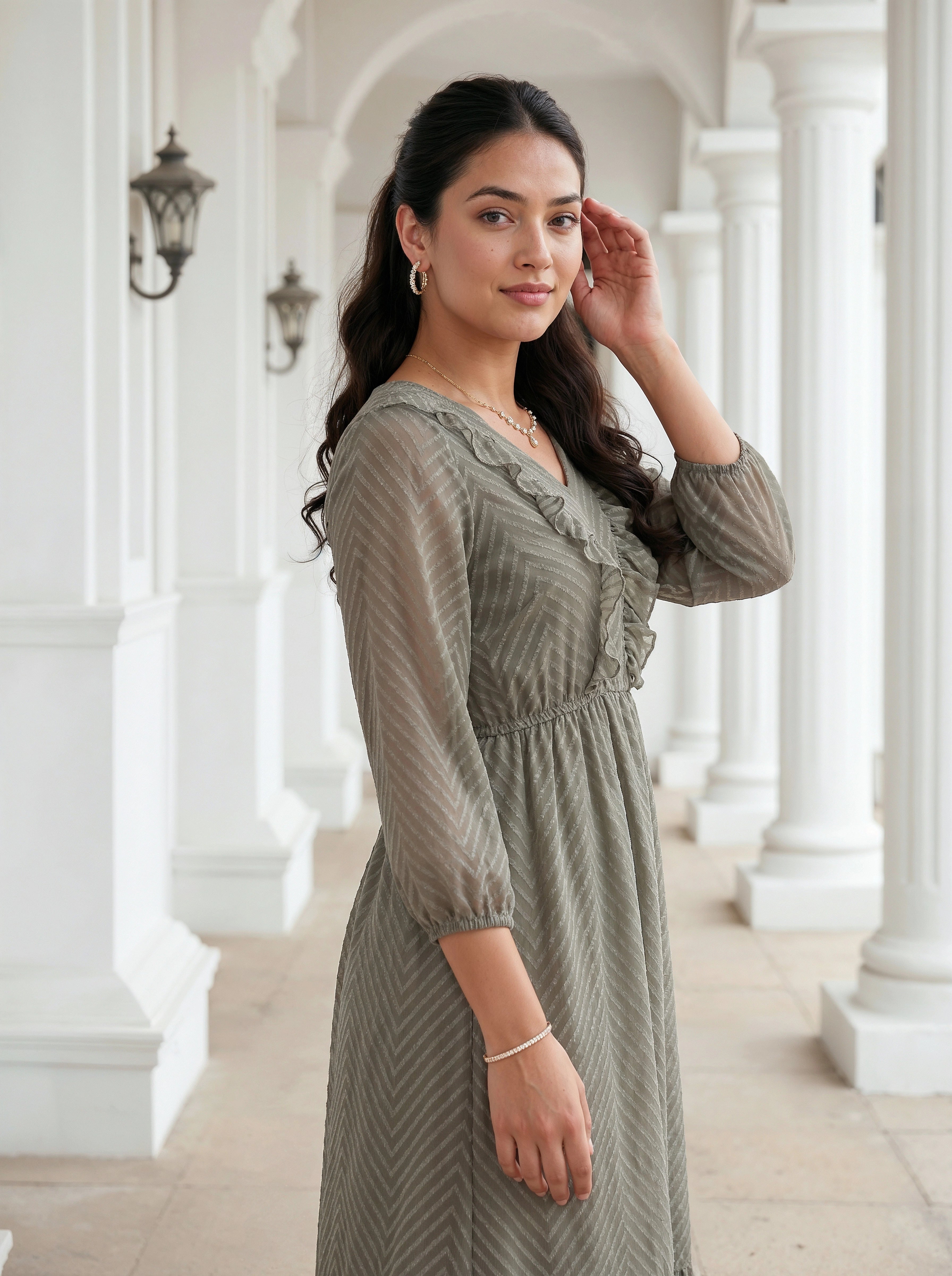 Woman in a green dress standing in a white architectural hallway