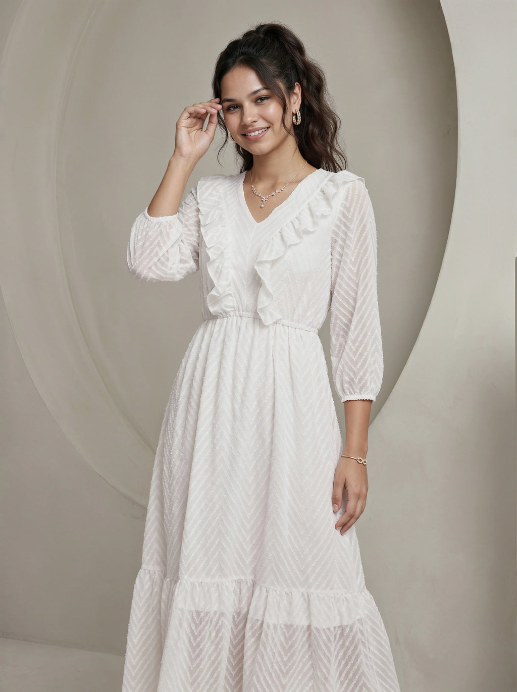 Woman wearing a white dress with ruffled sleeves against a neutral background