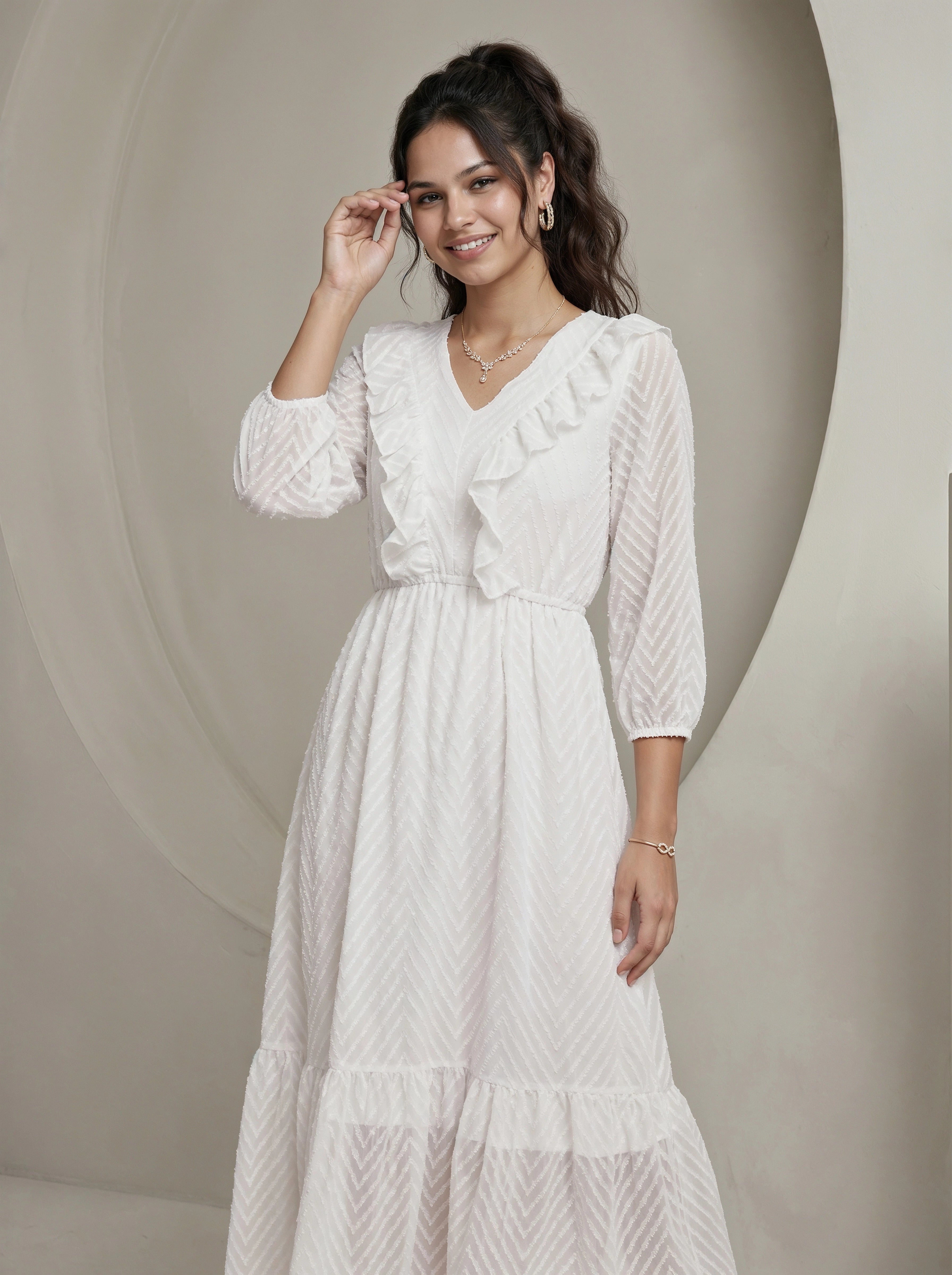 Woman wearing a white dress with ruffled sleeves against a neutral background