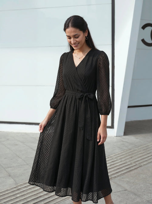 Woman wearing a black dress standing in front of a modern building.