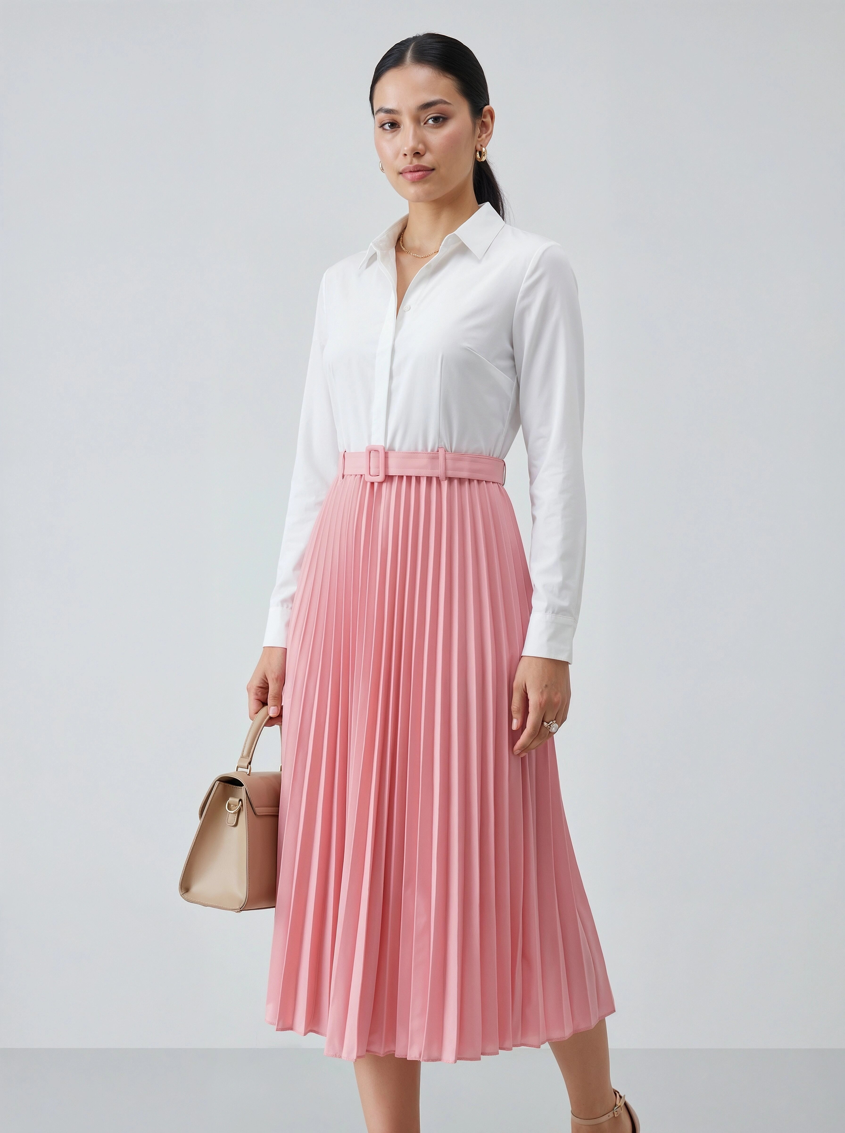 Woman wearing a white shirt and pink pleated skirt holding a beige handbag on a light gray background