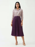 Woman wearing a floral blouse and purple pleated skirt on a white background
