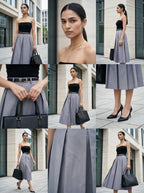 Woman wearing a black top and gray skirt with a black handbag, set against an urban background.