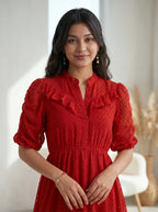 Woman wearing a navy blue dress with ruffled details, standing against a neutral background.