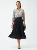 Woman wearing a floral blouse and black pleated skirt on a white background