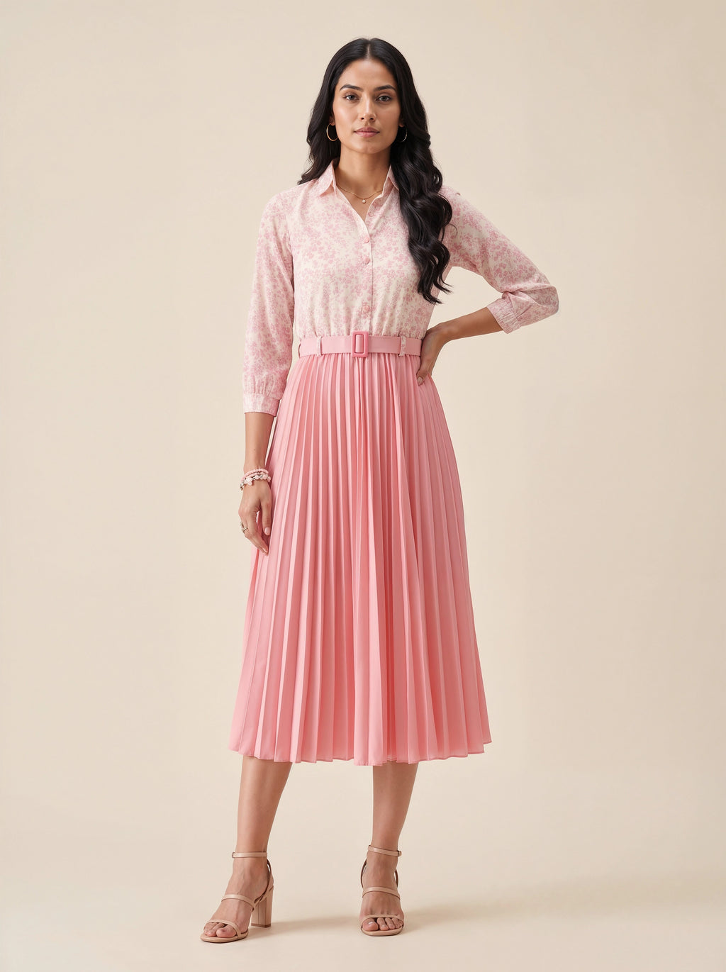 Woman wearing a pink lace blouse and pleated skirt on a beige background