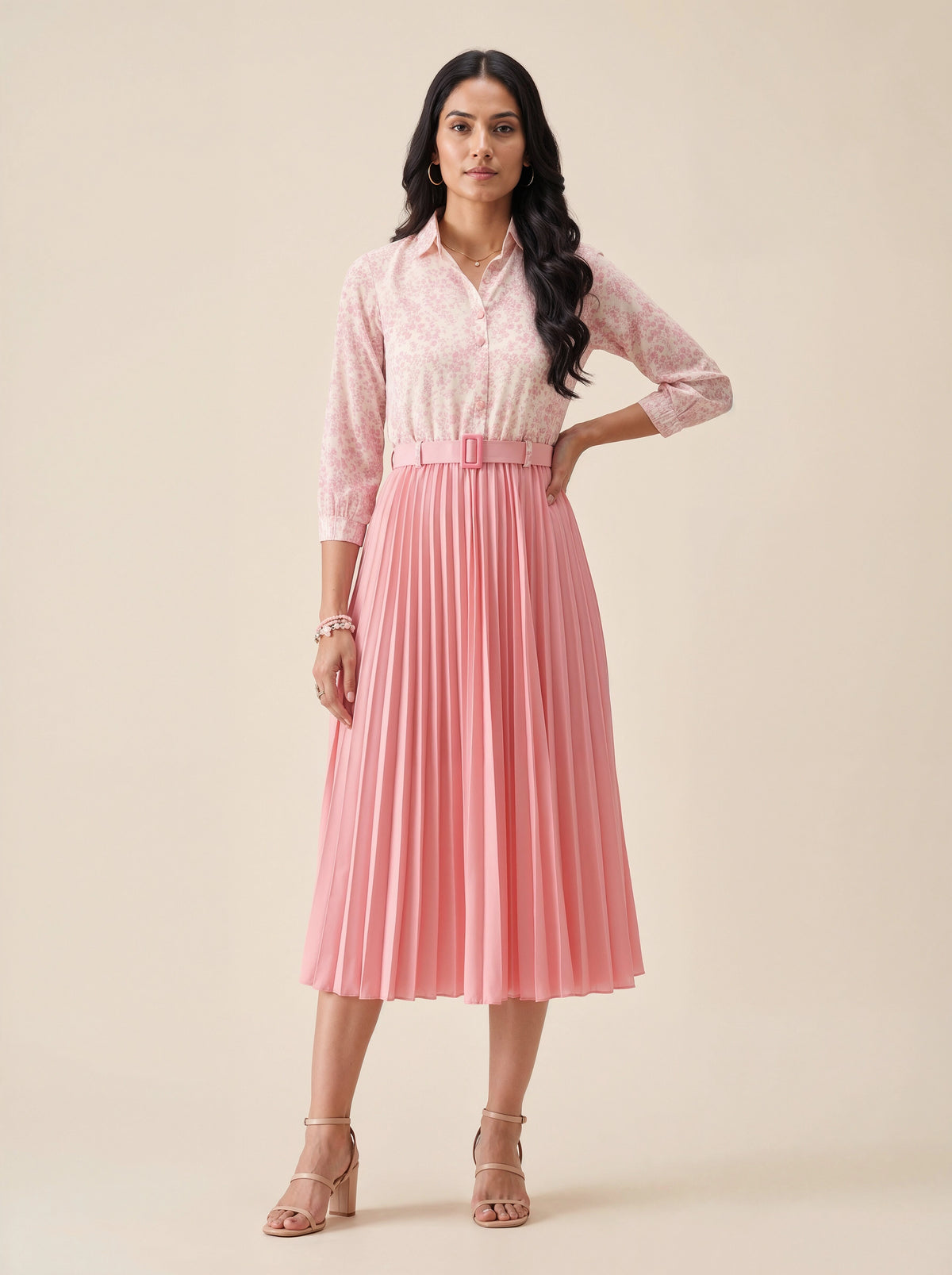 Woman wearing a pink lace blouse and pleated skirt on a beige background