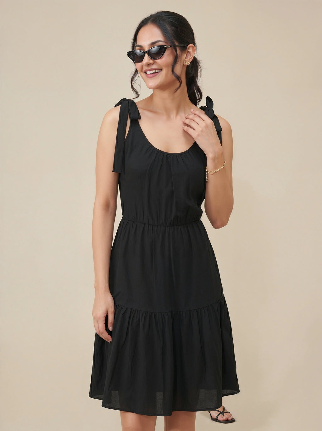Woman wearing a black dress with bow straps against a beige background