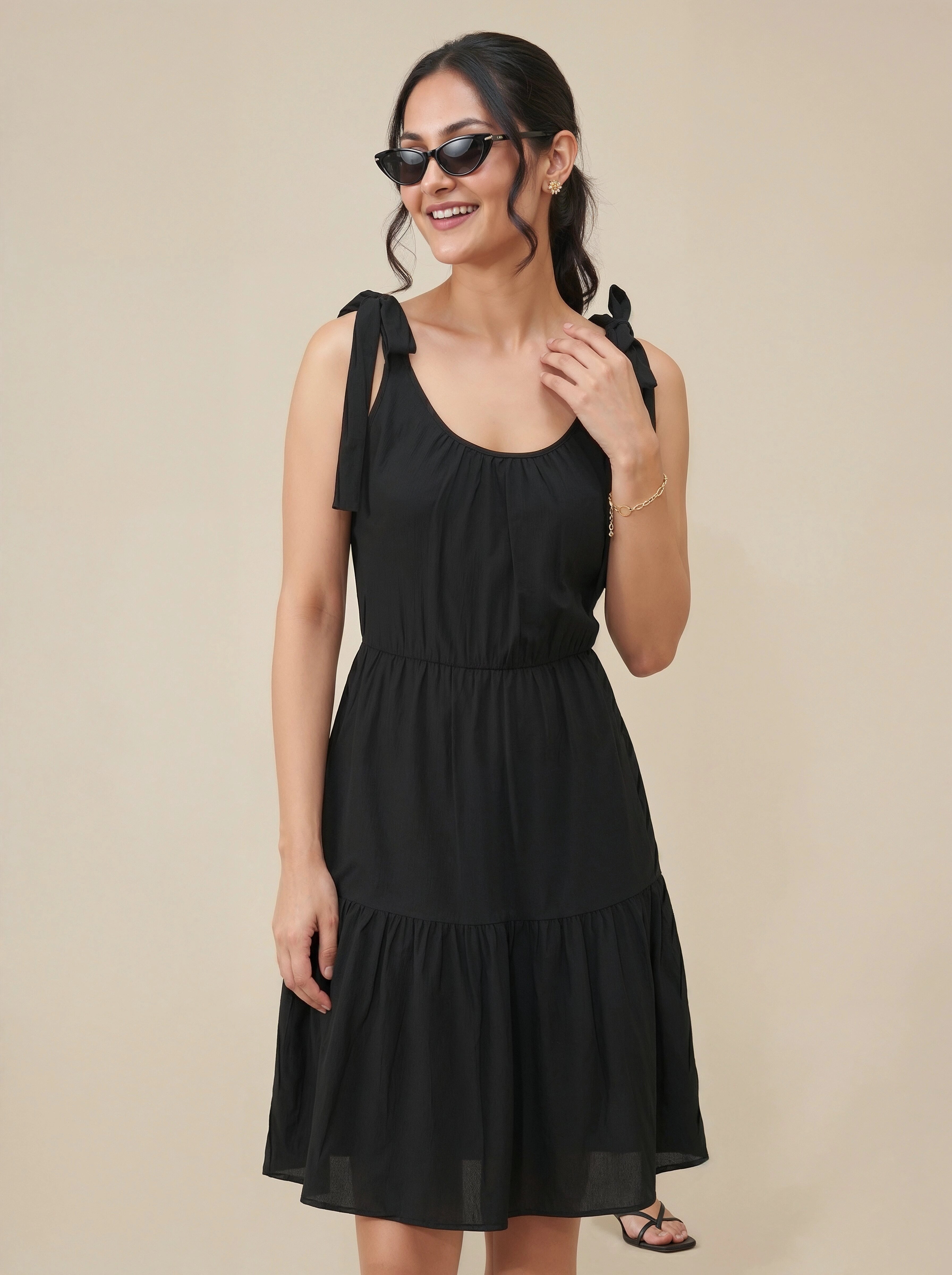 Woman wearing a black dress with bow straps against a beige background