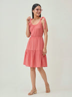 Woman wearing a coral dress with shoulder straps on a white background