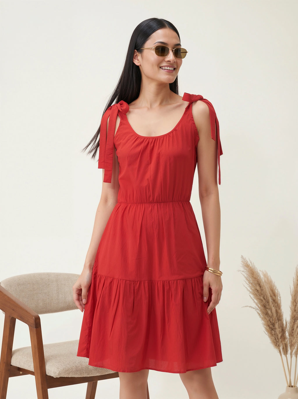 Woman wearing a red dress with bow straps against a neutral background