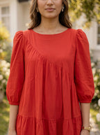 Woman wearing a red dress with puffed sleeves outdoors