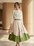 Woman wearing a green skirt with floral patterns in an indoor setting.