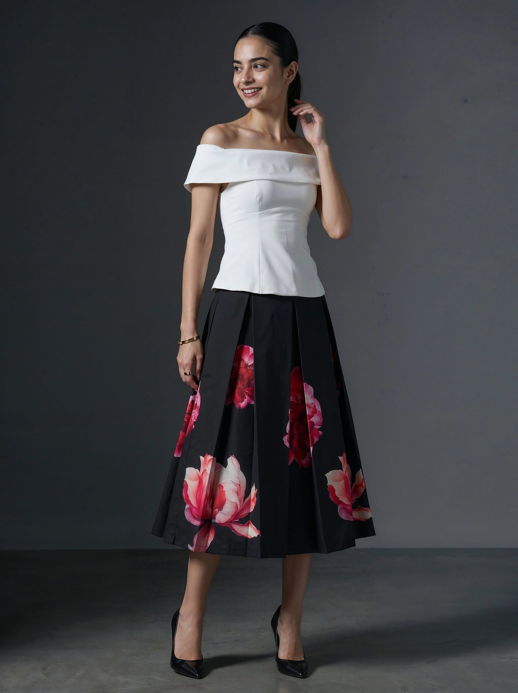 Woman wearing a white top and black floral skirt against a gray background