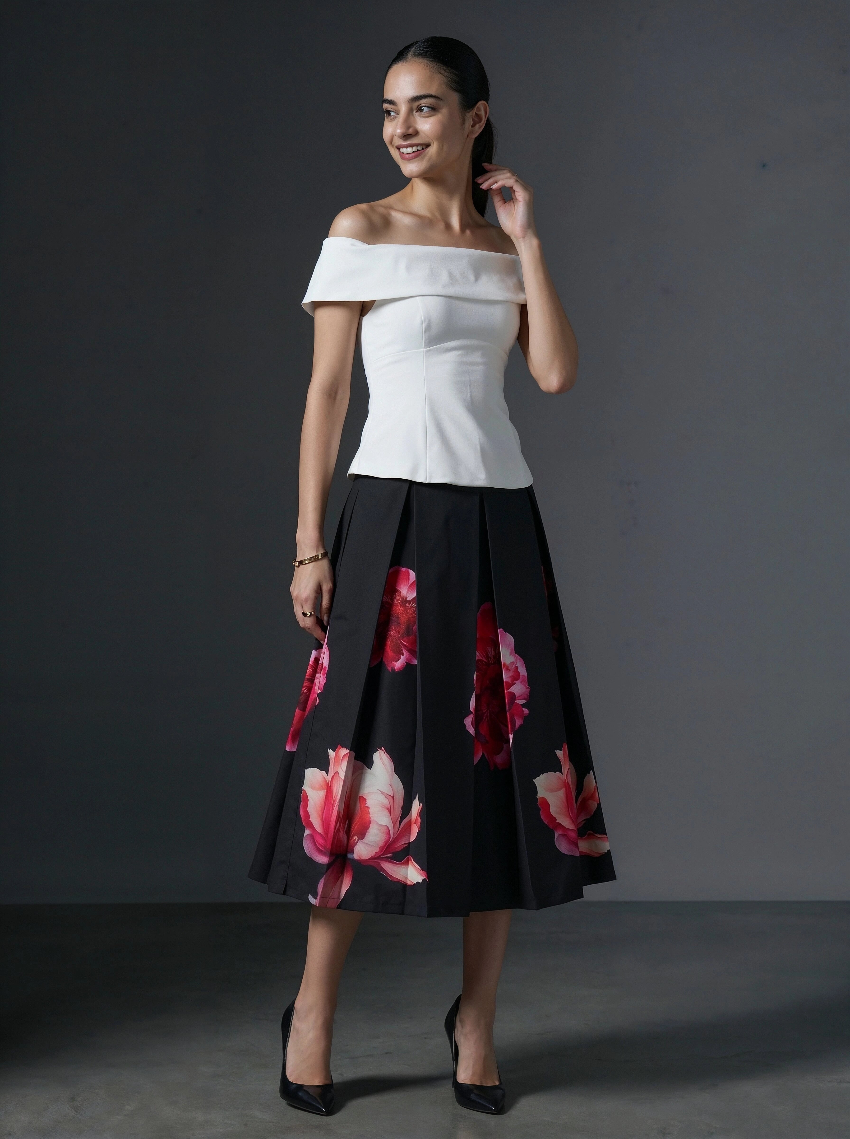 Woman wearing a white top and black floral skirt against a gray background
