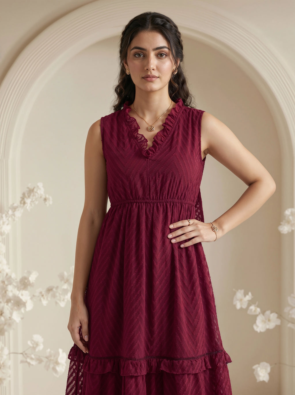Woman wearing a burgundy dress with floral decorations in a softly lit room.