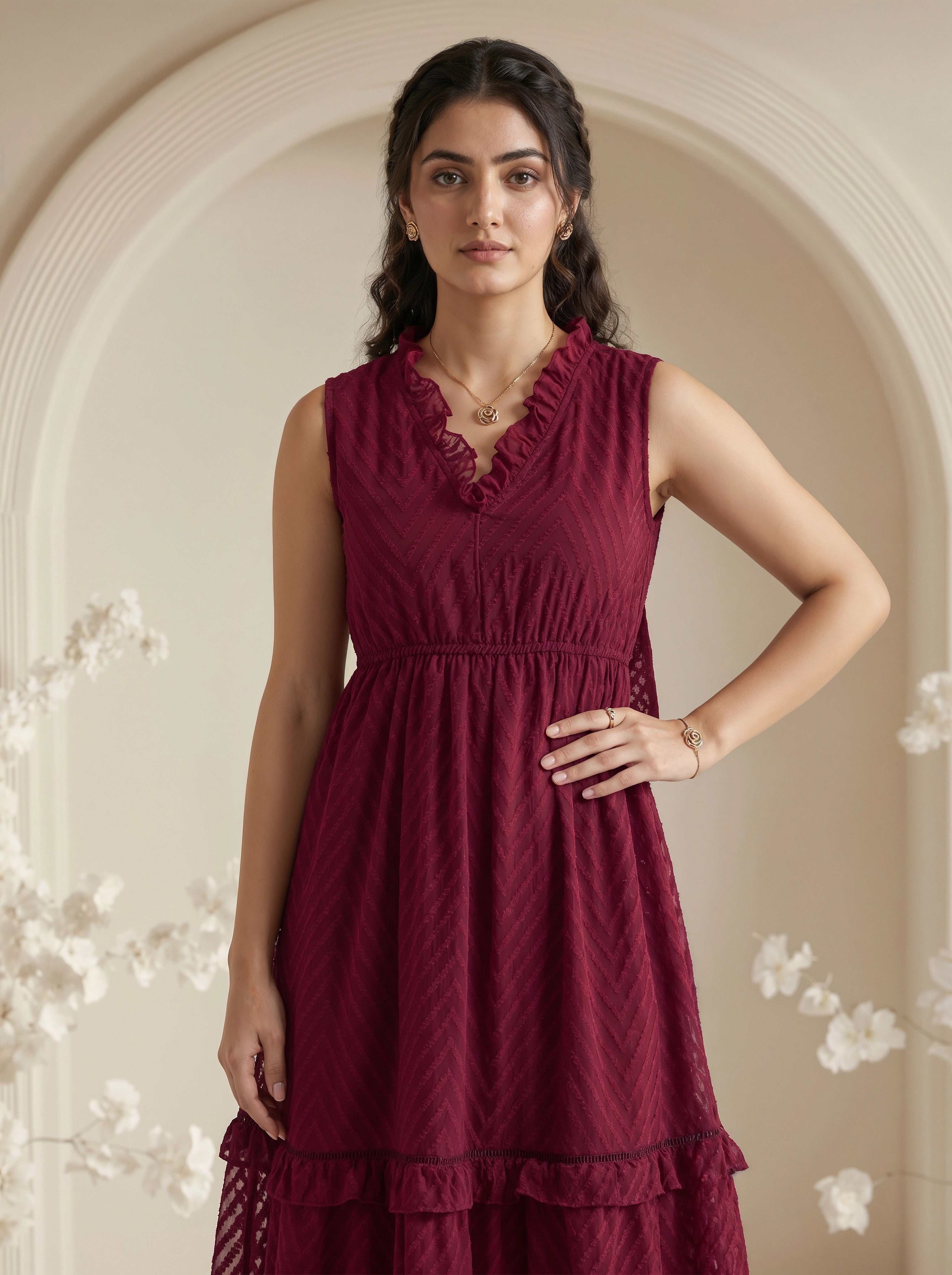 Woman wearing a burgundy dress with floral decorations in a softly lit room.