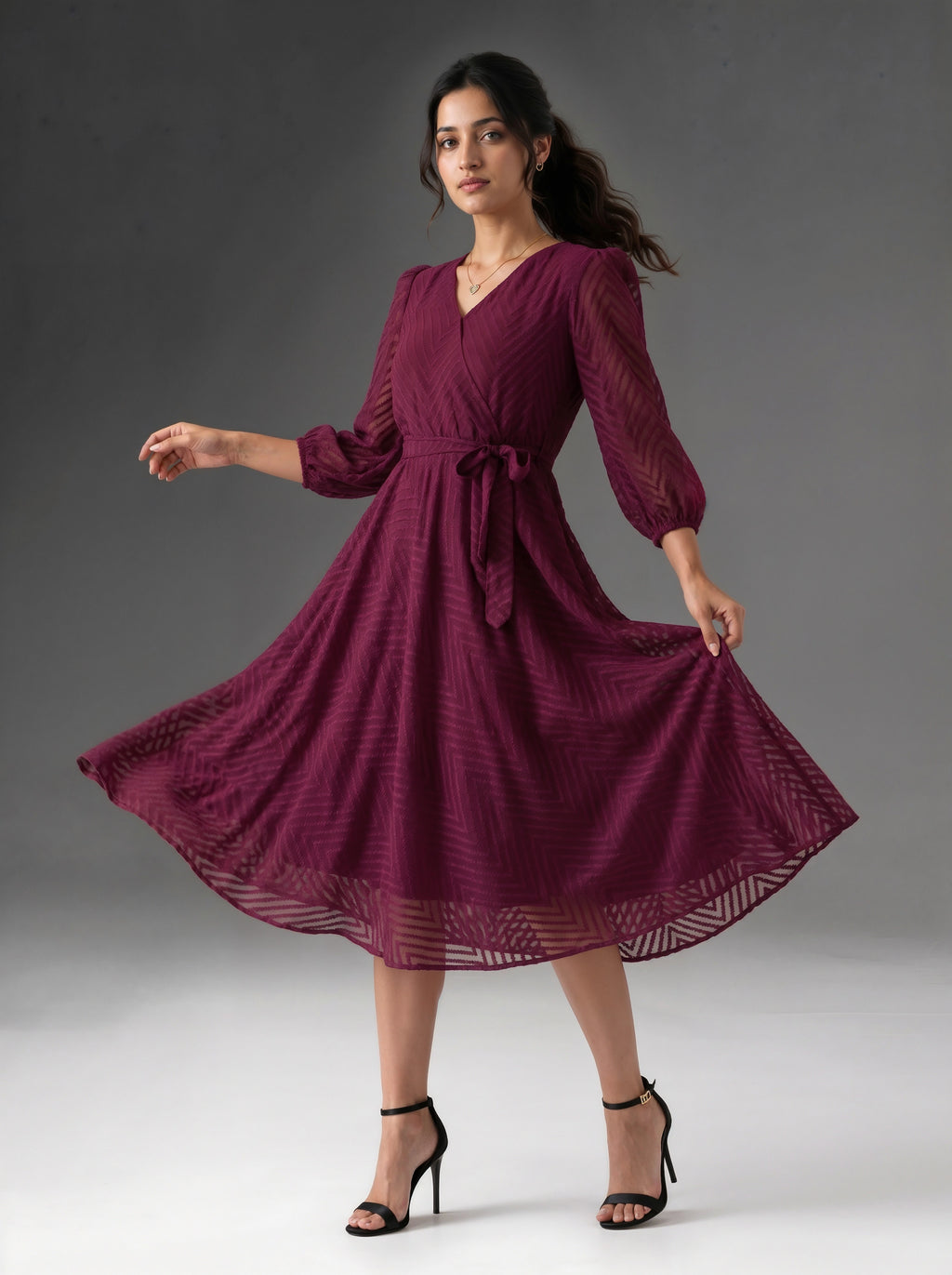 Woman wearing a burgundy dress with long sleeves on a gray background