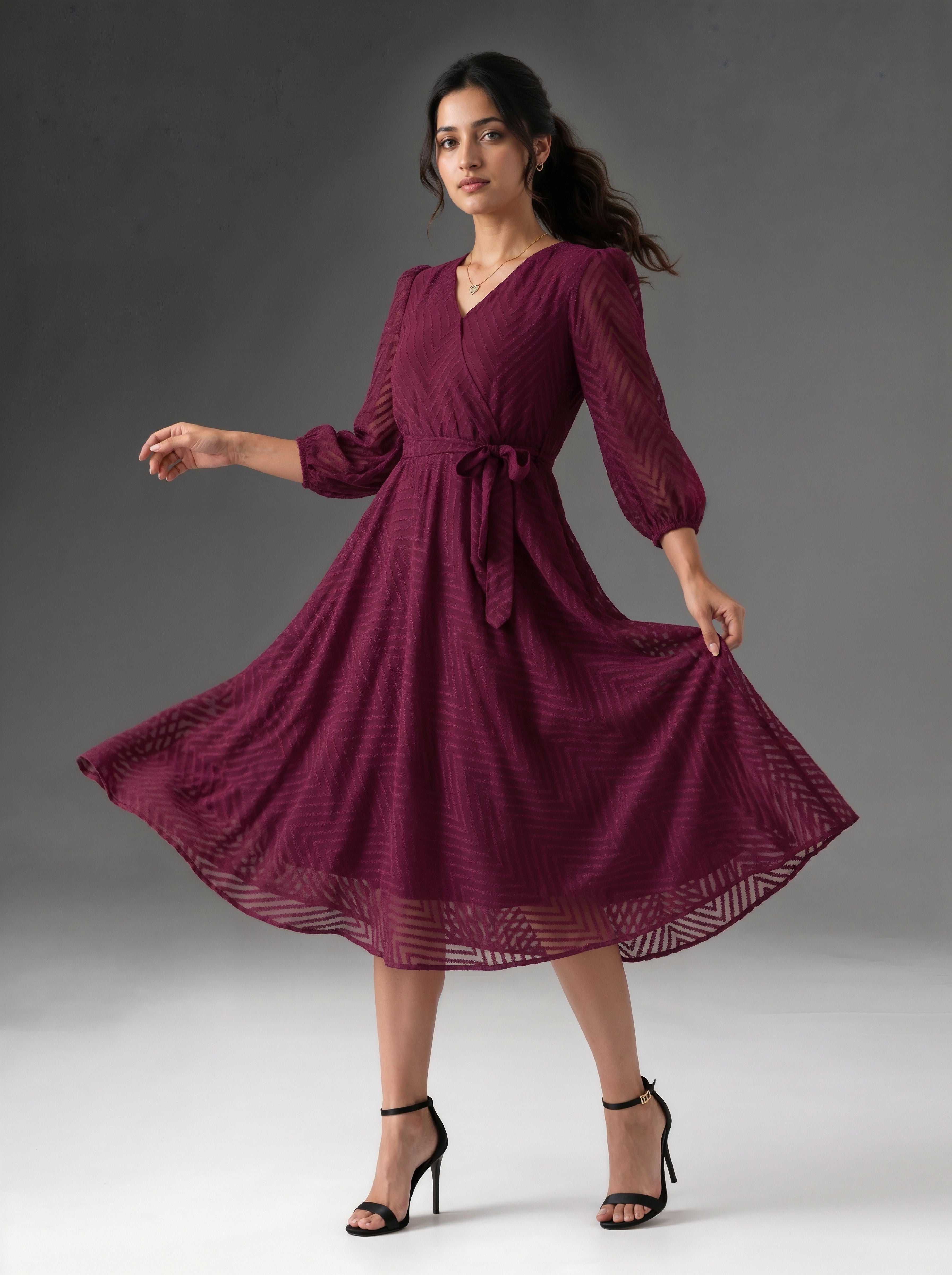 Woman wearing a burgundy dress with long sleeves on a gray background