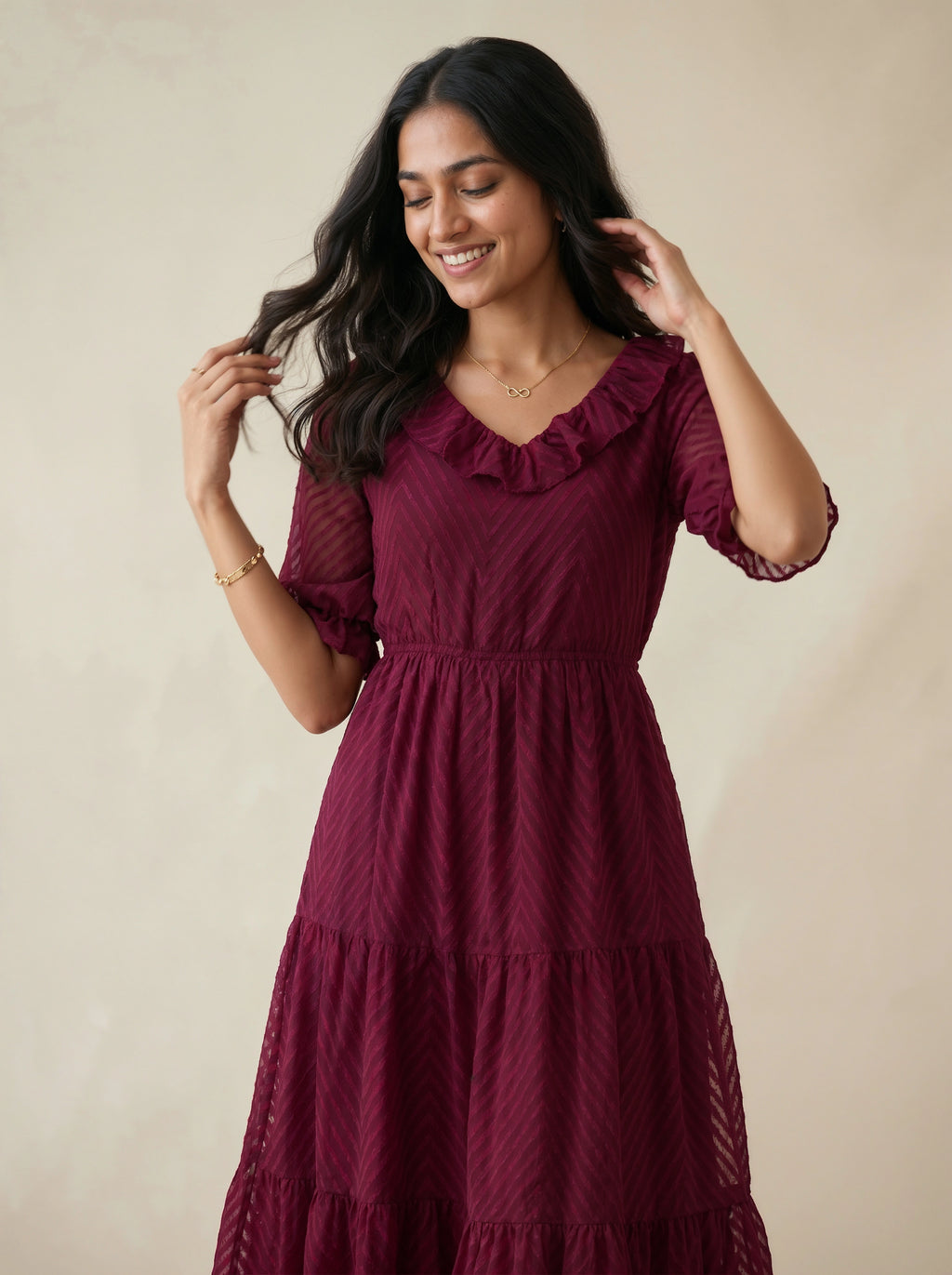 Woman wearing a burgundy dress with ruffled details against a beige background