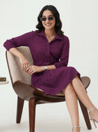 Woman in a purple dress sitting on a chair against a white background