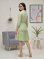 Woman in a light green dress standing in a modern living room.