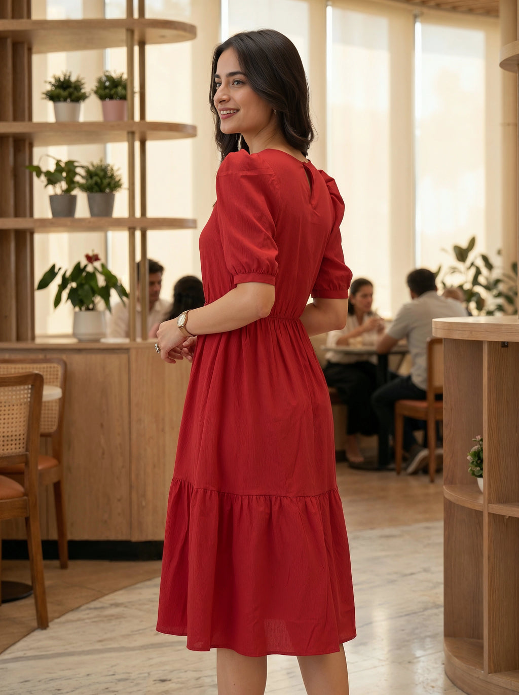 Woman in a red dress standing in a modern cafe with wooden interior.