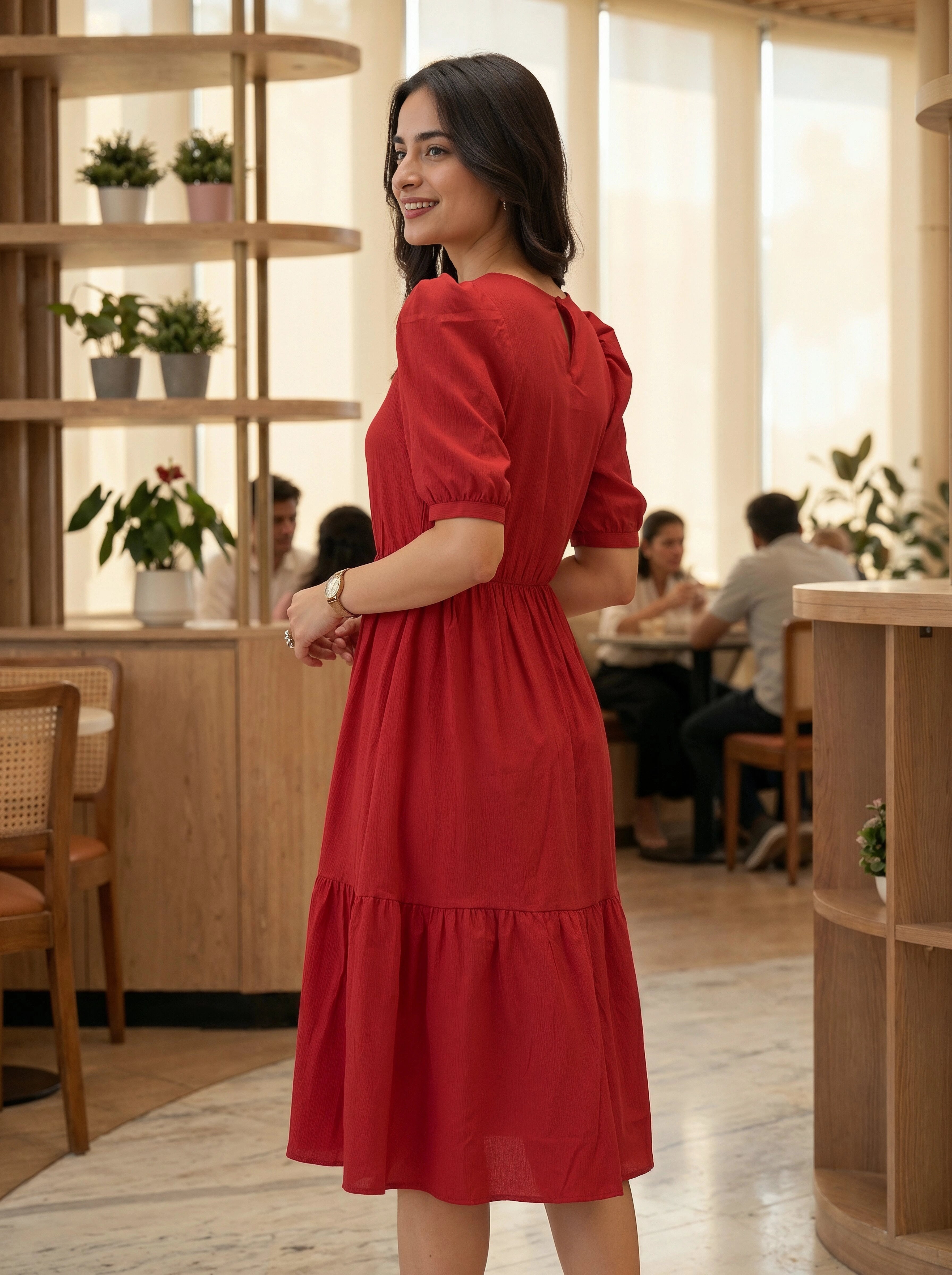 Woman in a red dress standing in a modern cafe with wooden interior.