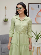 Woman wearing a light green dress with sunglasses indoors.
