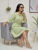 Woman in a light green dress sitting on a gray chair in a modern interior setting.