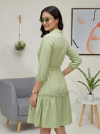 Woman wearing a light green dress in a living room setting