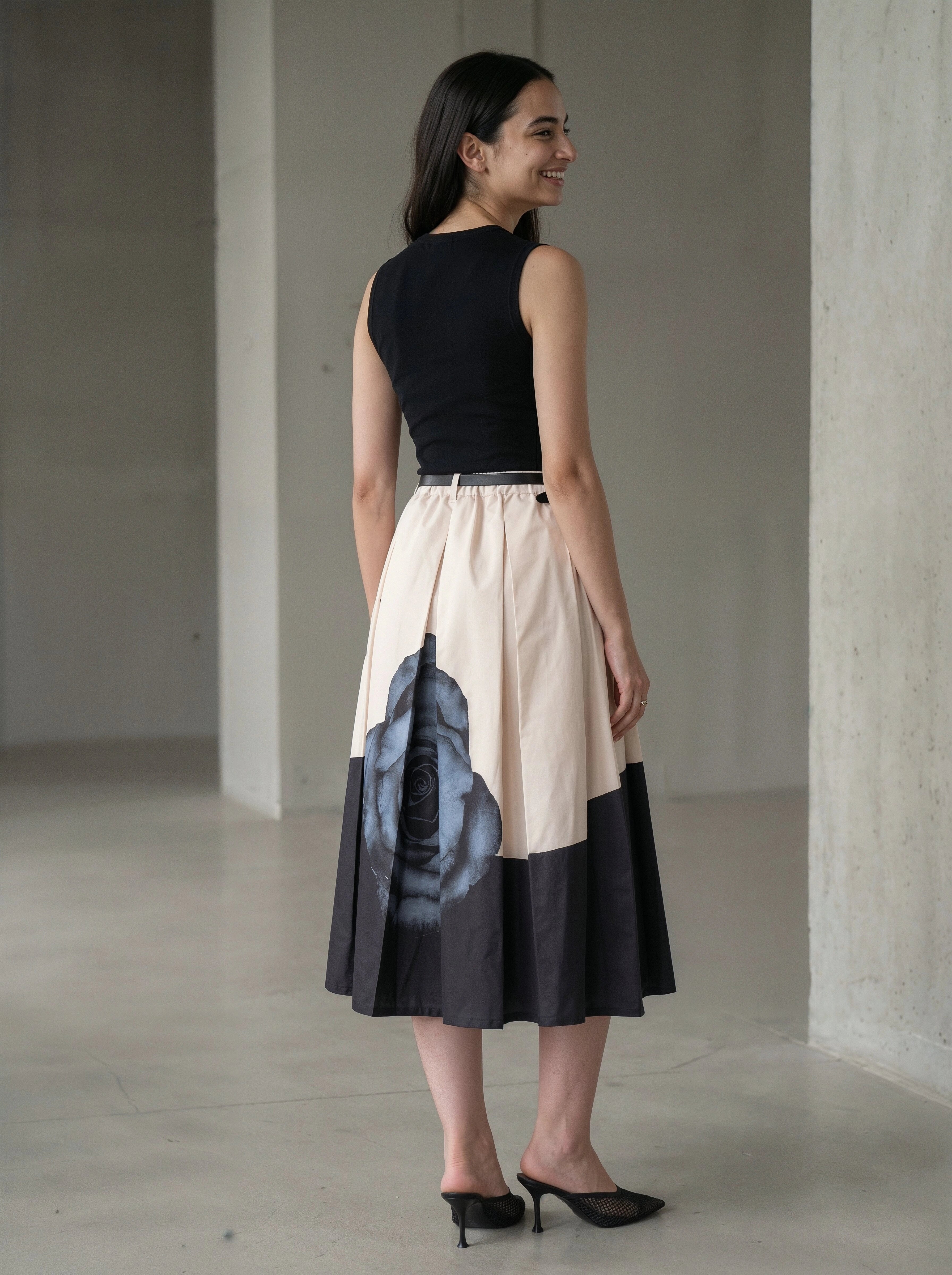 Woman wearing a black and beige dress with abstract design in a minimalistic setting